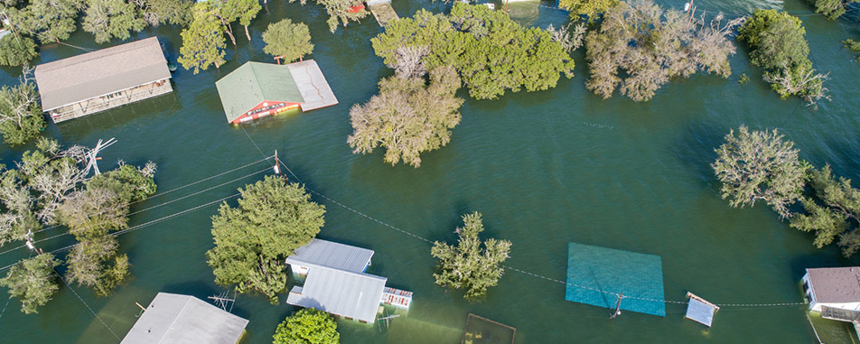 Aerial view of a flooded neighborhood with submerged homes and trees