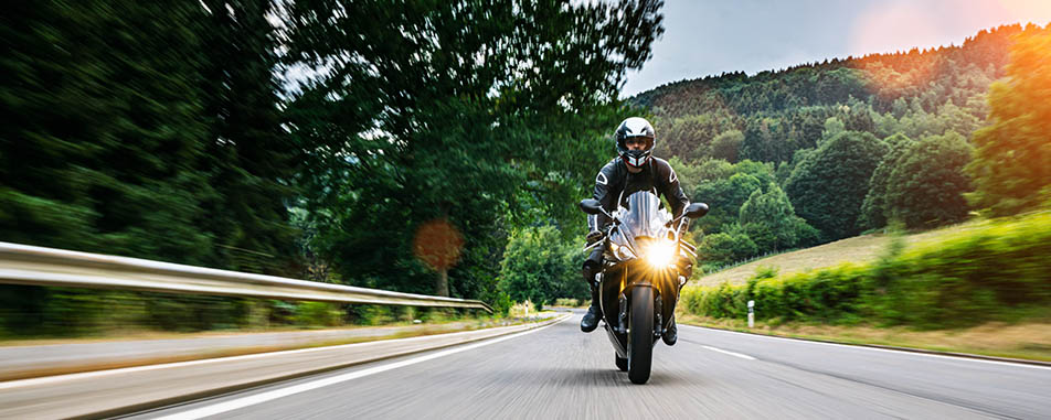 Motorcyclist in black gear rides on a forest road at high speed