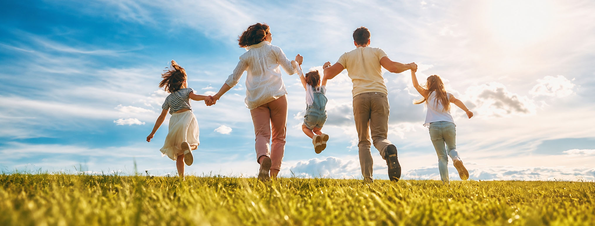 A family joyfully running together in a grassy field, arms around each other, showcasing love and togetherness.